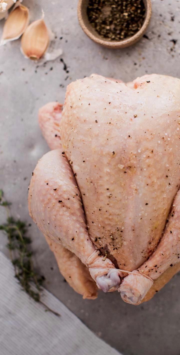 Whole raw chicken with rosemary